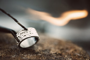 Fire and Ice. Close-Up View of Beautiful Silver Ring on Jeweler Workbench Ready For Soldering.